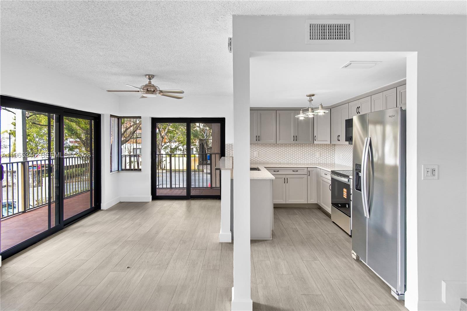 An open-concept kitchen with gray cabinetry and light wood-look flooring leads to a balcony — 4705 SW 62nd Ave # 204, Davie FL 33314, DAVIE, FL