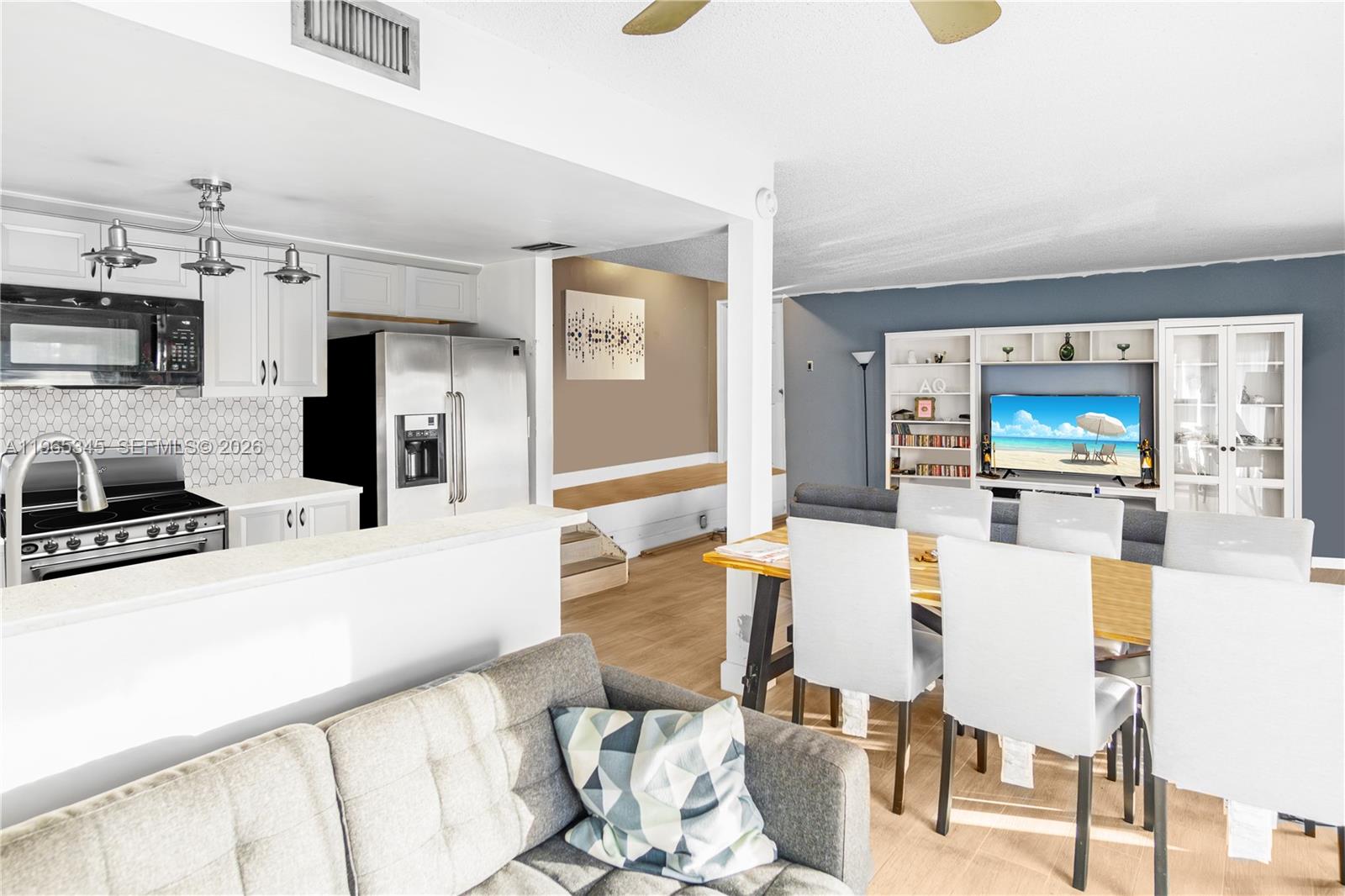 An open-concept living and dining area features a kitchen with white cabinets and stainless appliances — 4705 SW 62nd Ave # 204, Davie FL 33314, DAVIE, FL