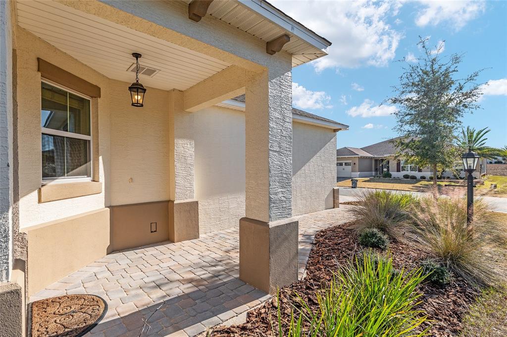 A covered entryway features a paver floor, a hanging lantern, and a stucco exterior — 9698 SW 103RD TERRACE, OCALA, FL