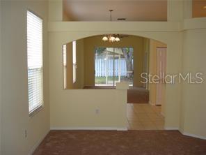 An interior view showing a carpeted room with an arched opening leading to a tiled area — 6234 BLACKBERRY LANE, LAKEWOOD RANCH, FL