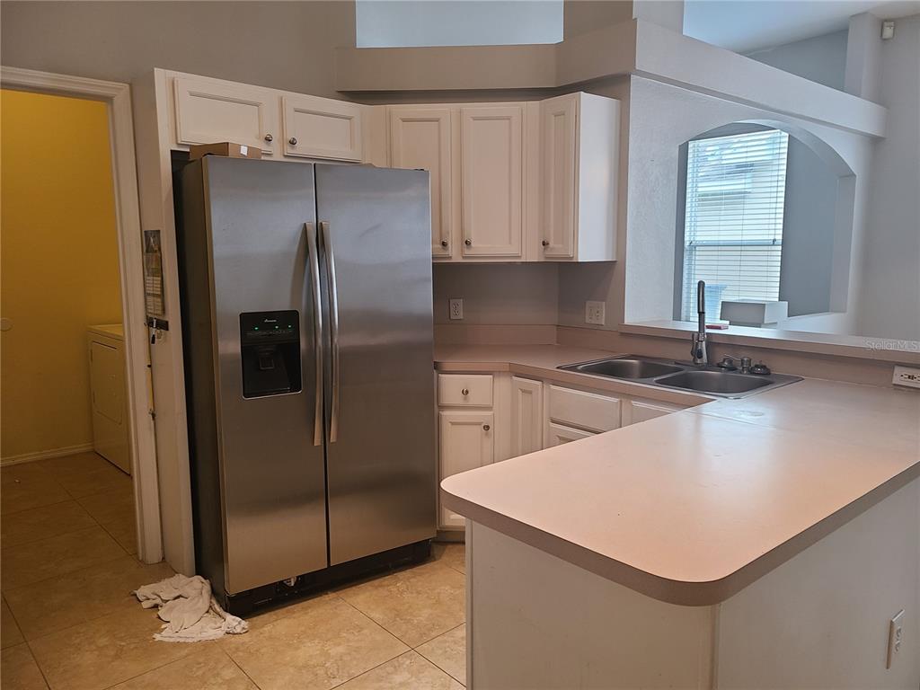 A kitchen features white cabinets, a stainless steel refrigerator, and a laminate countertop — 6234 BLACKBERRY LANE, LAKEWOOD RANCH, FL