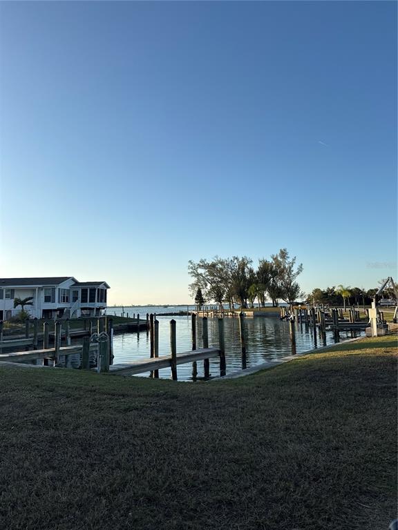 A waterfront view showing a house, wooden boat docks, and trees under a clear sky — 7500 PARK POINTE DRIVE UNIT 13, ENGLEWOOD, FL