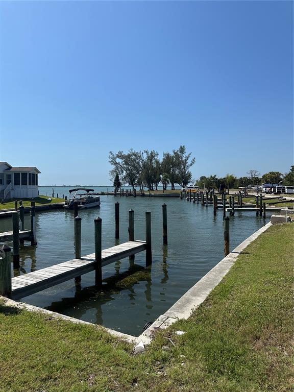 A canal view featuring a wooden dock, boat slips, and a small pontoon boat — 7500 PARK POINTE DRIVE UNIT 13, ENGLEWOOD, FL