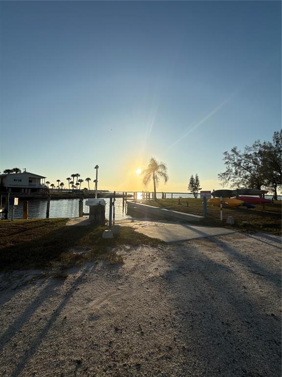 A boat ramp leads into a calm waterway at sunset with kayaks stored nearby — 7500 PARK POINTE DRIVE UNIT 13, ENGLEWOOD, FL