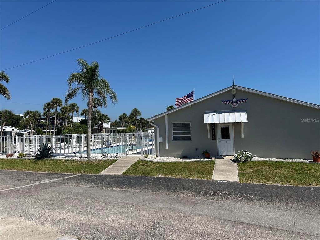 A single-story office building with a white door, metal awning, and an adjacent swimming pool — 7500 PARK POINTE DRIVE UNIT 13, ENGLEWOOD, FL