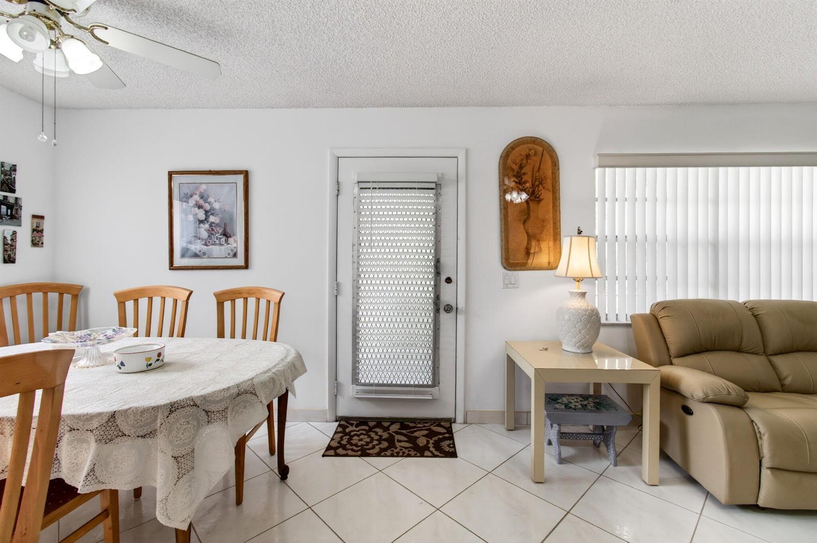 A dining area and living space with white tile floors, a ceiling fan, and furniture — 190 Piedmont D, Delray Beach FL 33484, DELRAY BEACH, FL