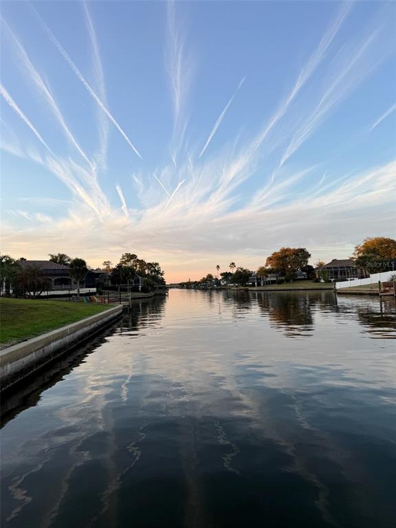 A view of a calm canal at sunset with houses along the grassy banks — 23 COMMANDER COURT, PALM COAST, FL