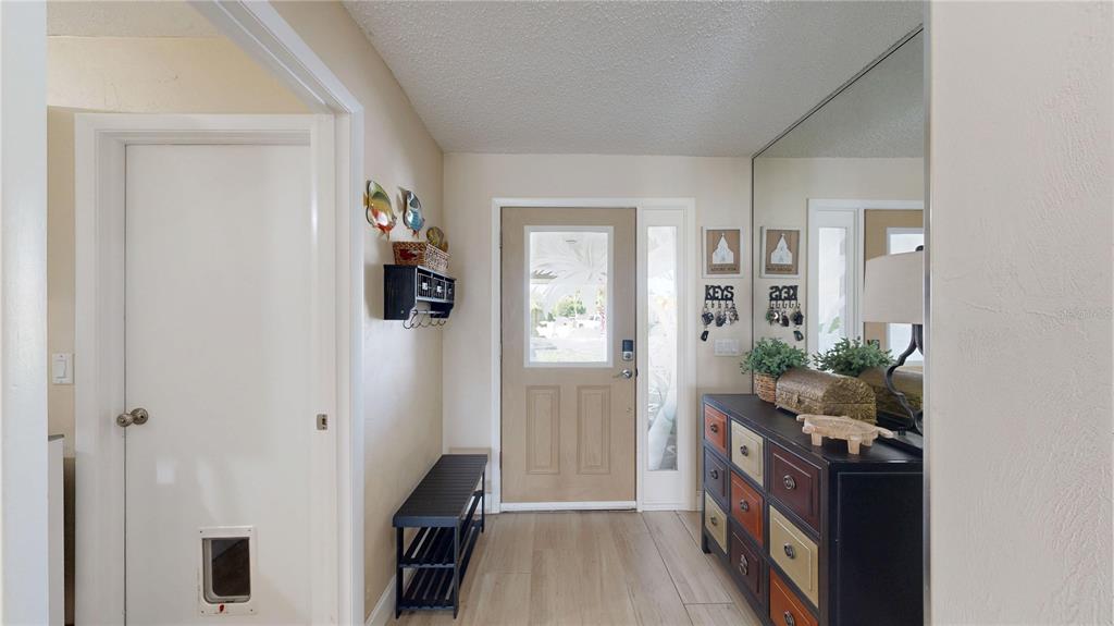 An entryway features a light-colored front door, a black shoe bench, and a multi-colored dresser — 23 COMMANDER COURT, PALM COAST, FL