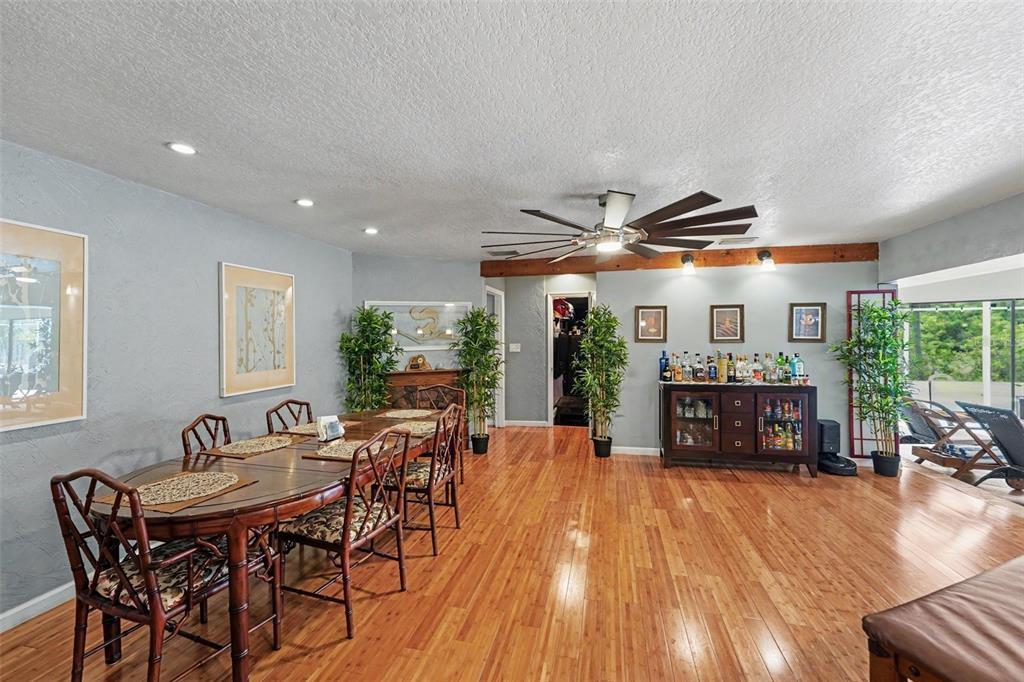 A dining room features a wooden table, bamboo-style chairs, a bar cabinet, and hardwood floors — 1615 SAINT PAULS DRIVE, CLEARWATER, FL