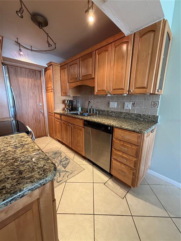 A kitchen features wood cabinets, granite countertops, stainless steel appliances, and light-colored tile flooring — 3806 GULF OF MEXICO DRIVE UNIT C211, LONGBOAT KEY, FL