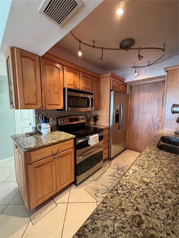 A kitchen features light wood cabinets, granite countertops, stainless steel appliances, and track lighting — 3806 GULF OF MEXICO DRIVE UNIT C211, LONGBOAT KEY, FL