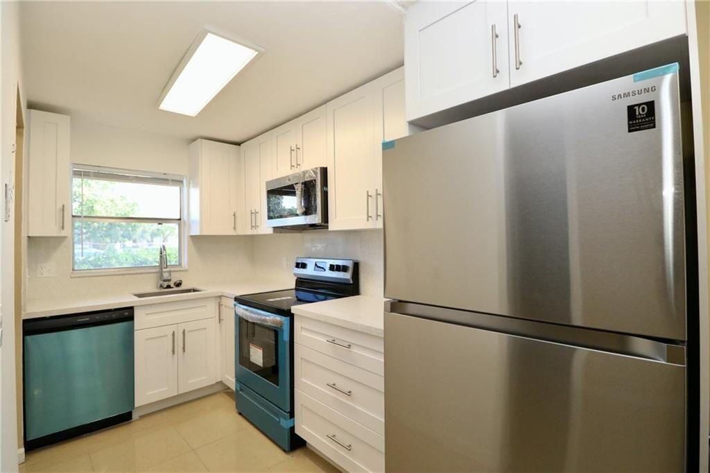 A kitchen features white cabinets, stainless steel appliances, and light-colored countertops — 9915 Sandalfoot Boulevard # 408, Boca Raton FL 33428, BOCA RATON, FL