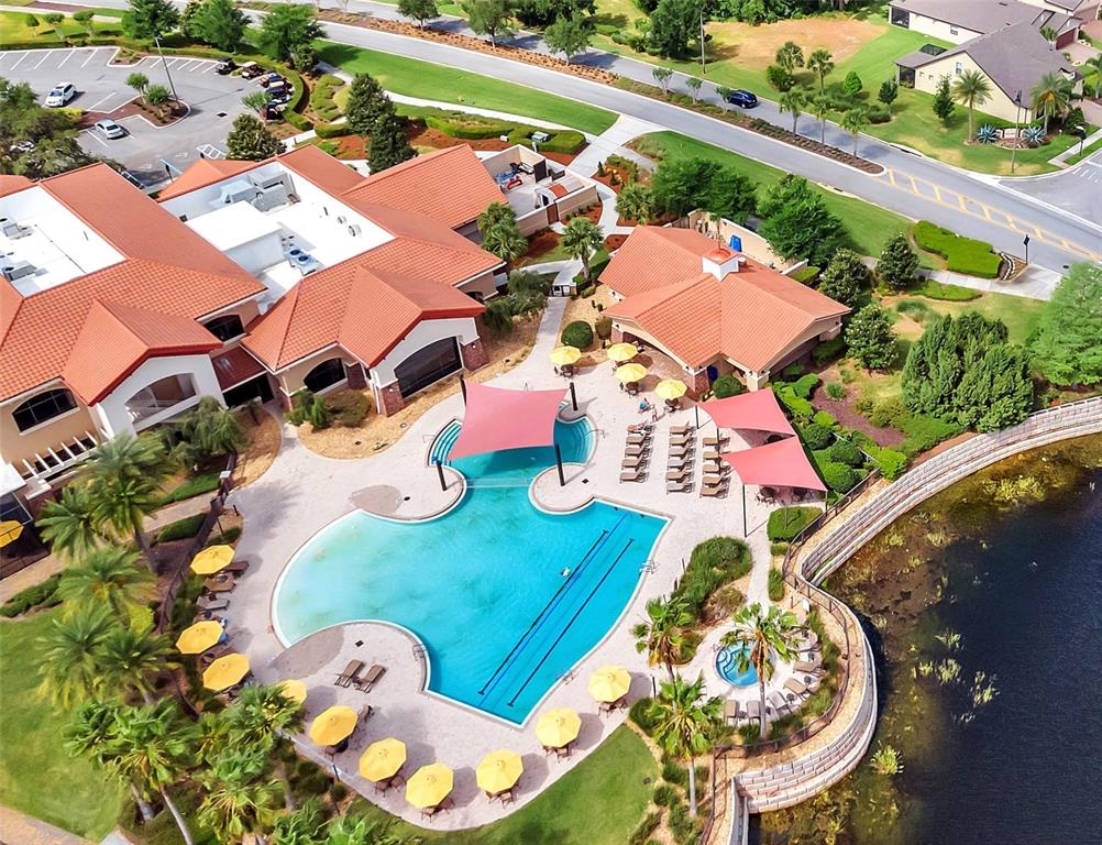 An aerial view shows a community swimming pool with lounge chairs and red shade sails — 423 ARMADA LANE, DAVENPORT, FL