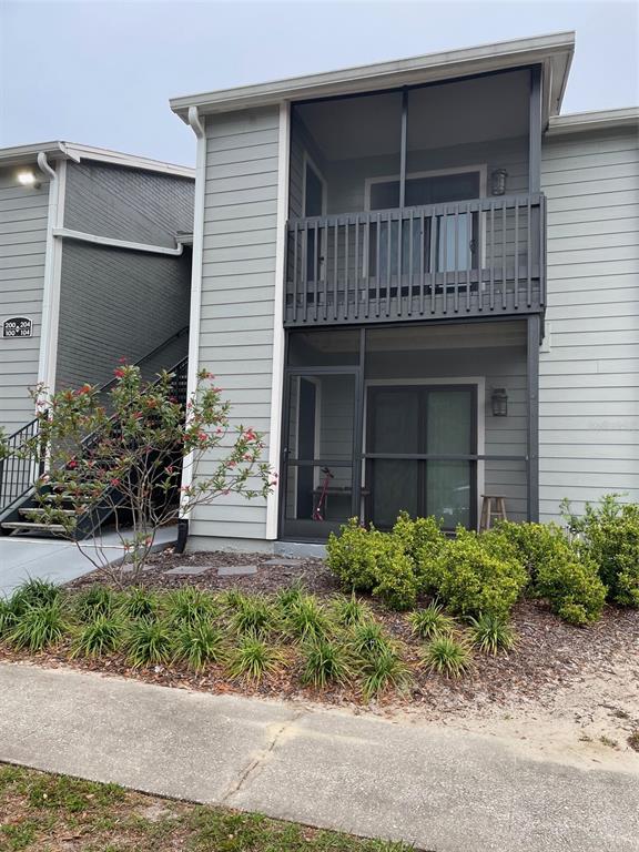 A two-story apartment building features gray siding, screened-in porches, and a metal staircase — 3764 IDLEBROOK CIRCLE UNIT 204, CASSELBERRY, FL