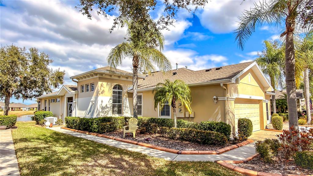 A single-story house with a tan exterior, a two-car garage, and palm trees in front — 2069 SIFIELD GREENS WAY UNIT 102, SUN CITY CENTER, FL