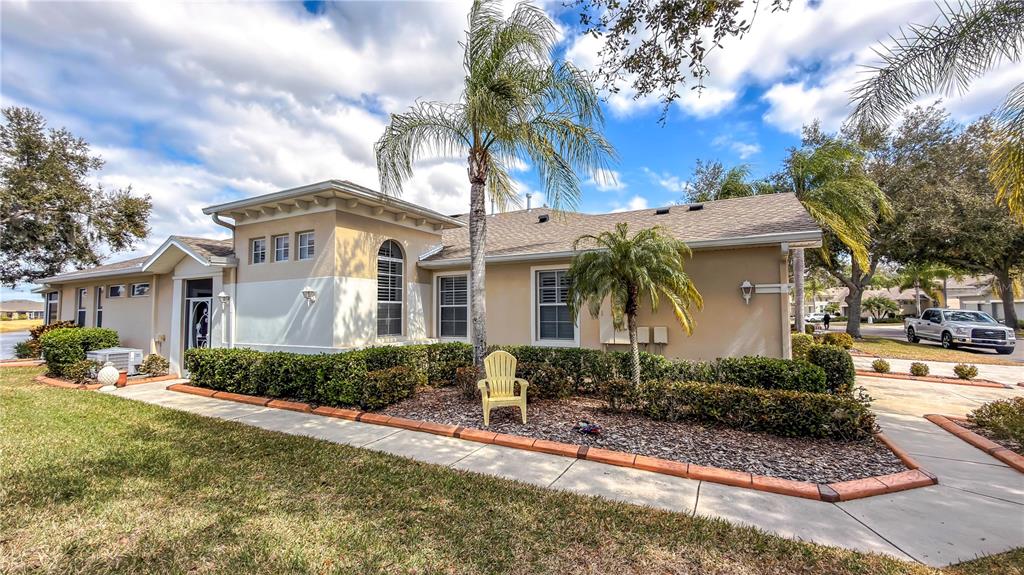 A single-story house with a beige exterior, a palm tree, and a yellow chair — 2069 SIFIELD GREENS WAY UNIT 102, SUN CITY CENTER, FL