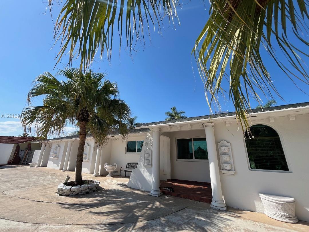 A white house exterior features a palm tree, decorative columns, and a paved courtyard — 2525 SW 107th Ct, Miami FL 33165, MIAMI, FL