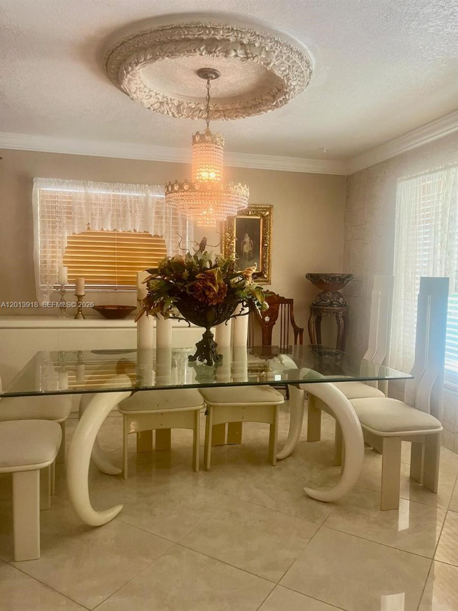 A dining room features a glass-topped table, upholstered chairs, and a crystal chandelier — 2525 SW 107th Ct, Miami FL 33165, MIAMI, FL