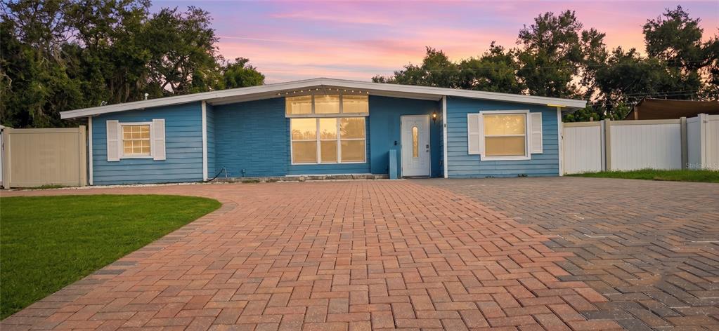 A blue single-story house with a brick paver driveway and white vinyl fencing — 3609 SCHWALBE DRIVE, SARASOTA, FL