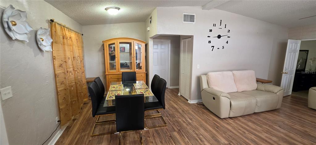 A dining area with a glass table and hutch sits beside a living room sofa — 3609 SCHWALBE DRIVE, SARASOTA, FL