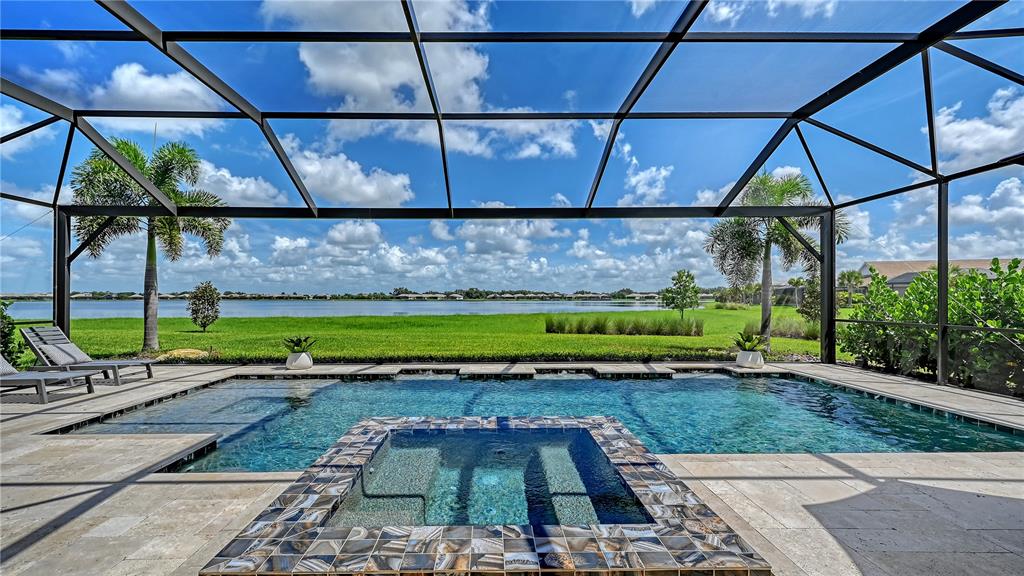 A screened-in pool and spa overlook a grassy lawn and a large lake — 7919 WATERBEND TRAIL, SARASOTA, FL