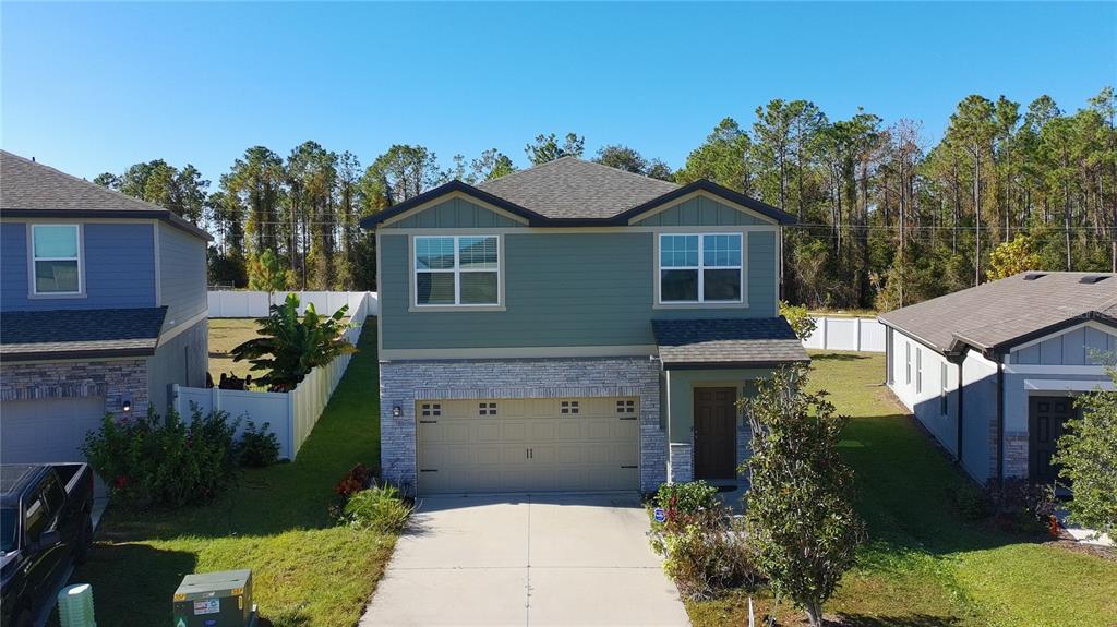 A two-story house with a green upper level, stone-veneer lower level, and a two-car garage — 1991 HEMINGWAY CIRCLE, GROVELAND, FL