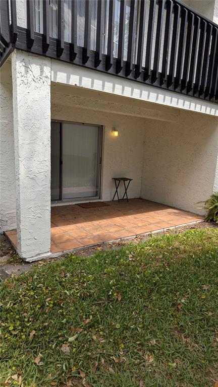 A ground-floor patio with tiled flooring, a sliding glass door, and a small folding table — 4401 S SEMORAN BOULEVARD UNIT 9, ORLANDO, FL