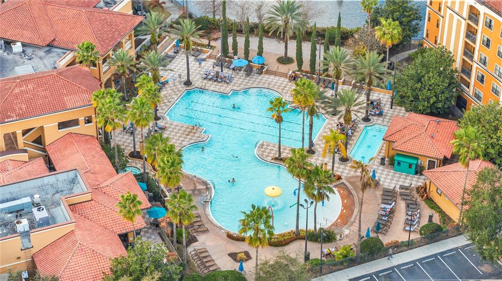An aerial view shows a large swimming pool complex surrounded by buildings with red-tiled roofs — 12527 FLORIDAYS RESORT DRIVE UNIT 402E, ORLANDO, FL