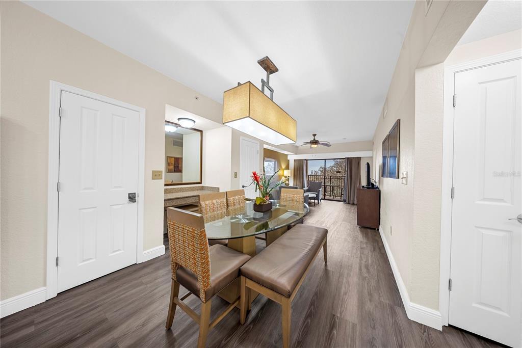 A dining area with a glass table, bench seating, and a large rectangular pendant light — 12527 FLORIDAYS RESORT DRIVE UNIT 402E, ORLANDO, FL