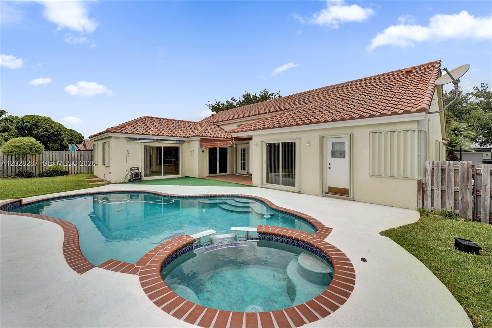 A spacious living room features light wood flooring, a vaulted ceiling, and a crystal chandelier — 8860 Southern Orchard Rd S, Davie FL 33328, DAVIE, FL