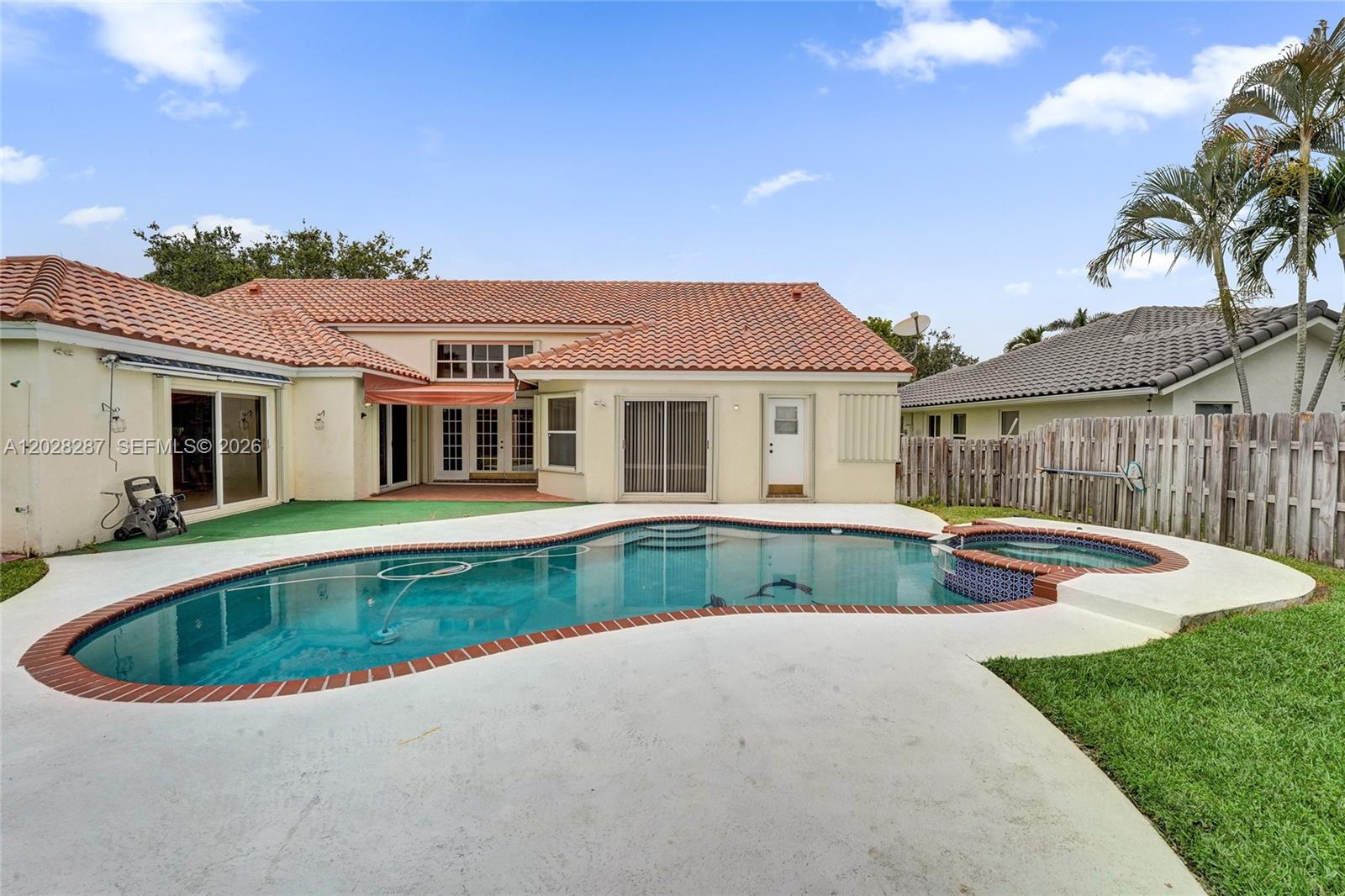 A bright living room features high ceilings, a beige sofa, armchairs, and a pool view — 8860 Southern Orchard Rd S, Davie FL 33328, DAVIE, FL