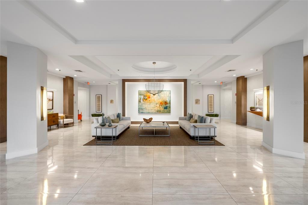 A spacious, modern lobby features marble floors, two facing sofas, and a central abstract painting — 3060 GRAND BAY BOULEVARD UNIT 133, LONGBOAT KEY, FL