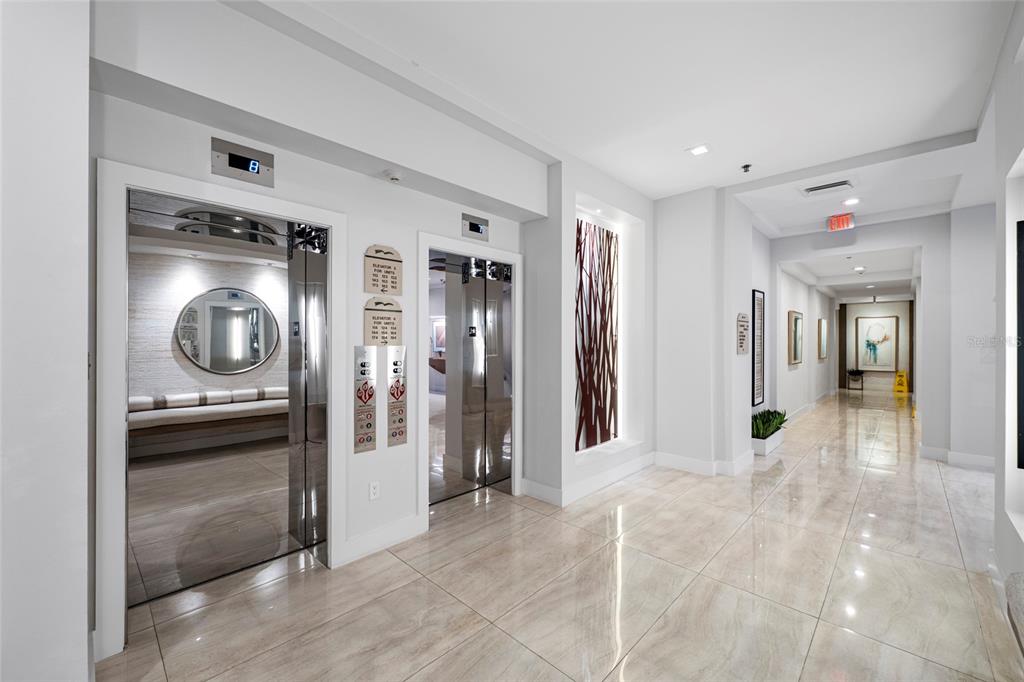 A bright elevator lobby with polished tile floors, two mirrored elevators, and a long hallway — 3060 GRAND BAY BOULEVARD UNIT 133, LONGBOAT KEY, FL