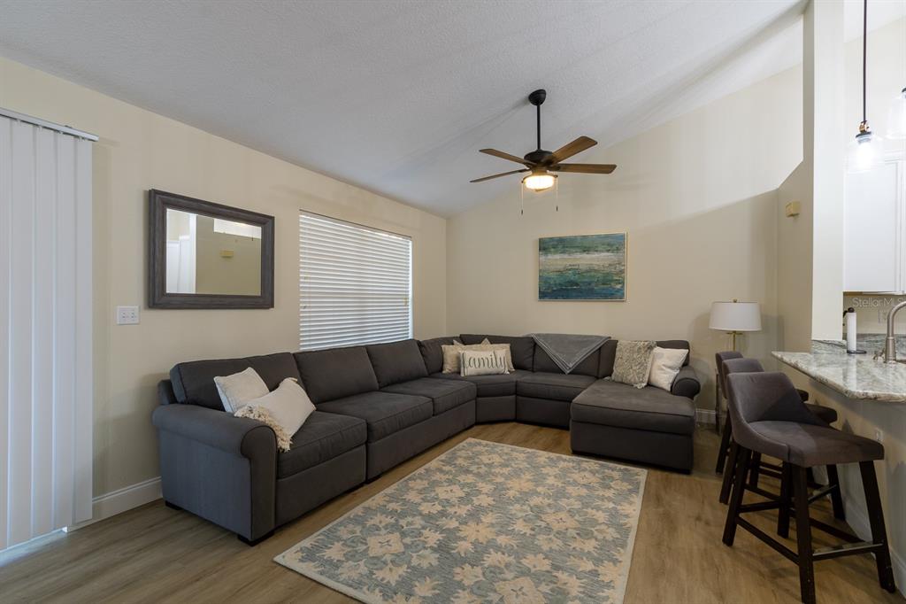 A living room features a large gray sectional sofa, a patterned rug, and a ceiling fan — 10000 SW 52ND AVENUE UNIT 60, GAINESVILLE, FL