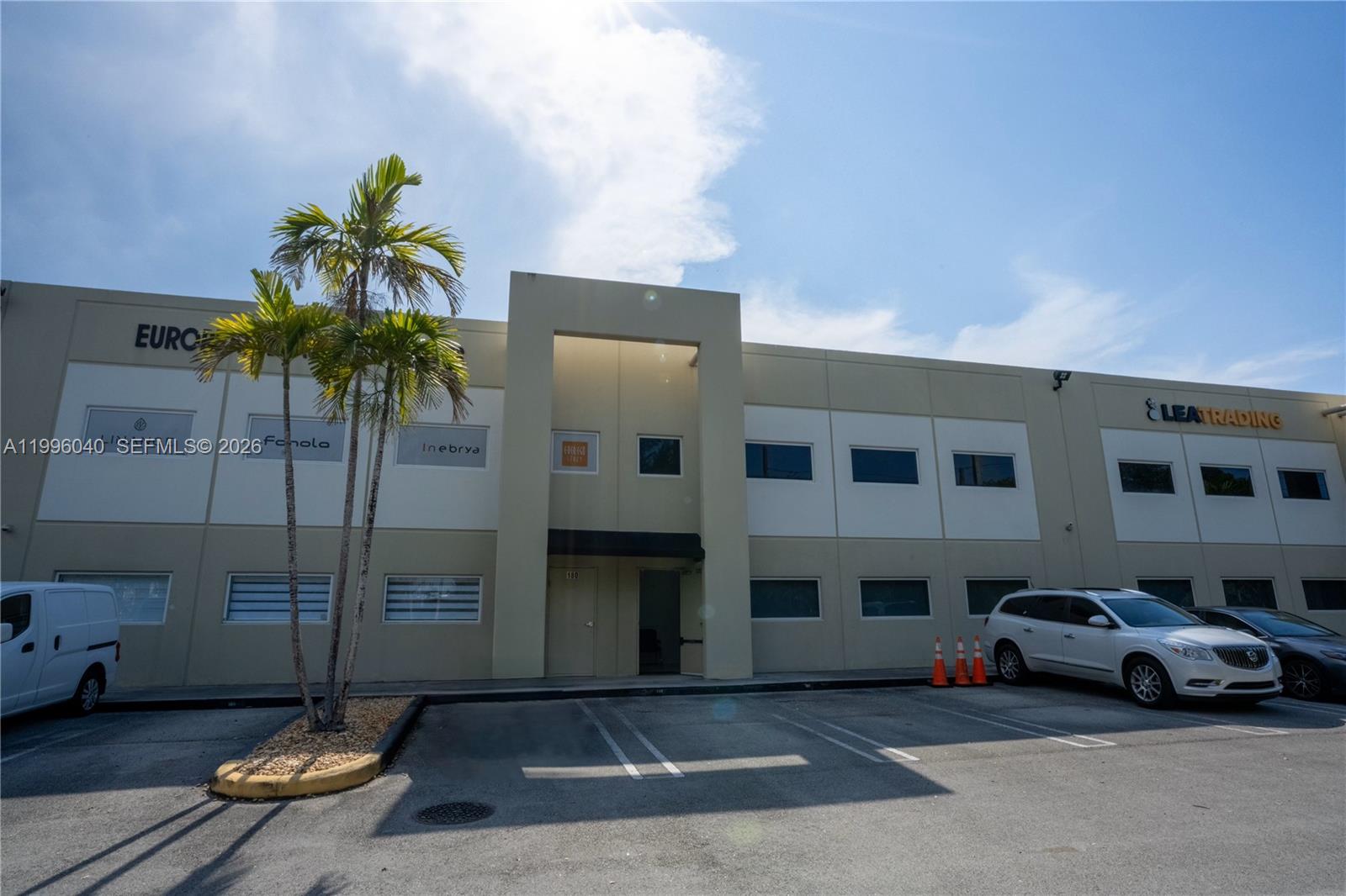 A two-story commercial building features a central entrance, parking spaces, and palm trees in front — 10800 NW 21St # 190, Doral FL 33172, DORAL, FL