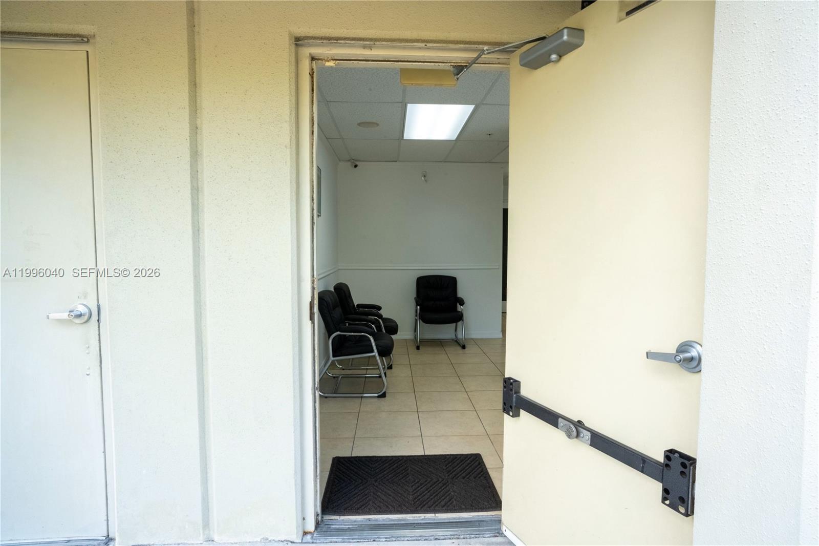 An open door reveals a small waiting area with three black chairs and tile flooring — 10800 NW 21St # 190, Doral FL 33172, DORAL, FL