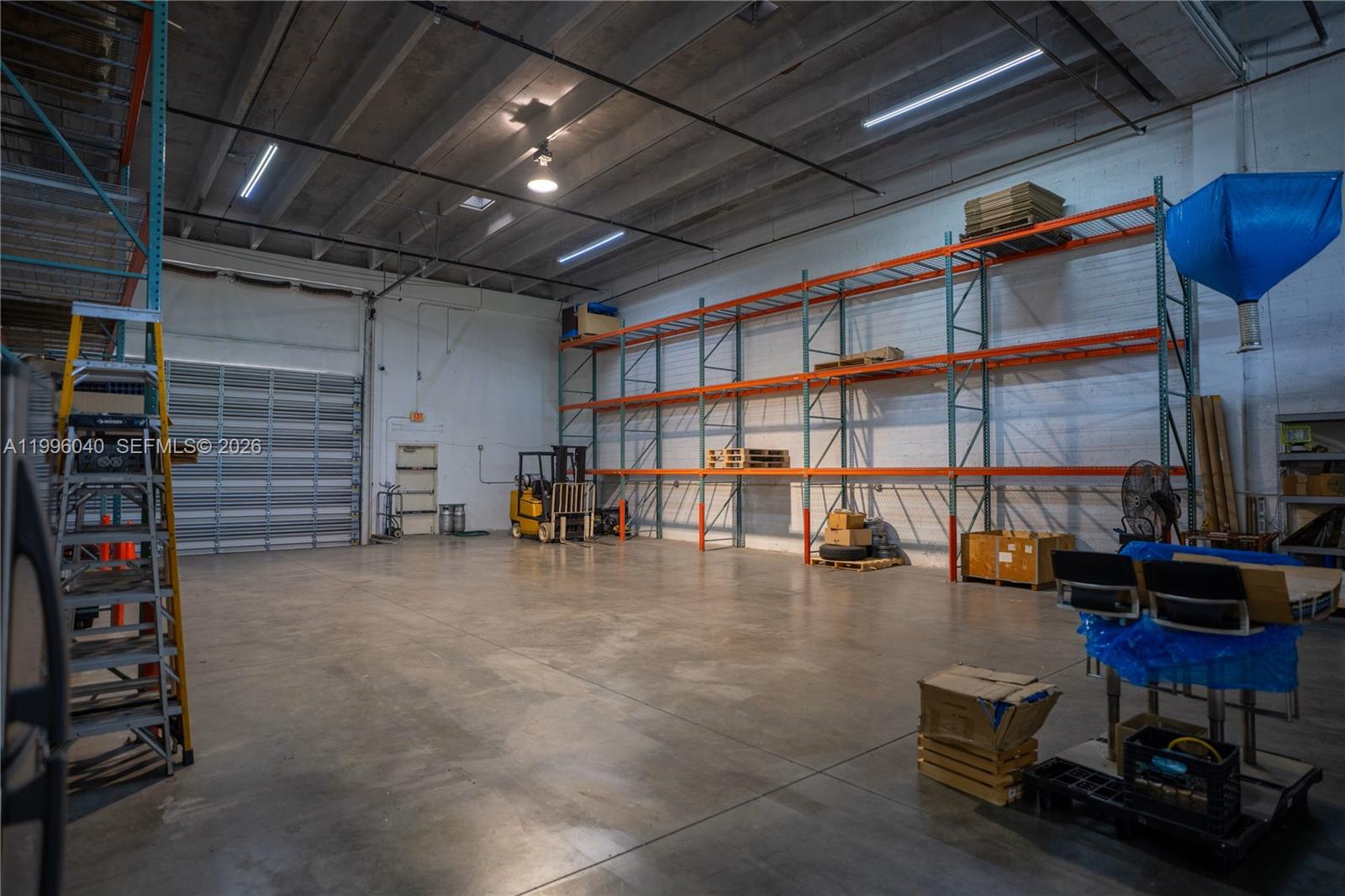 A warehouse space features concrete floors, high ceilings, industrial shelving units, and a forklift — 10800 NW 21St # 190, Doral FL 33172, DORAL, FL
