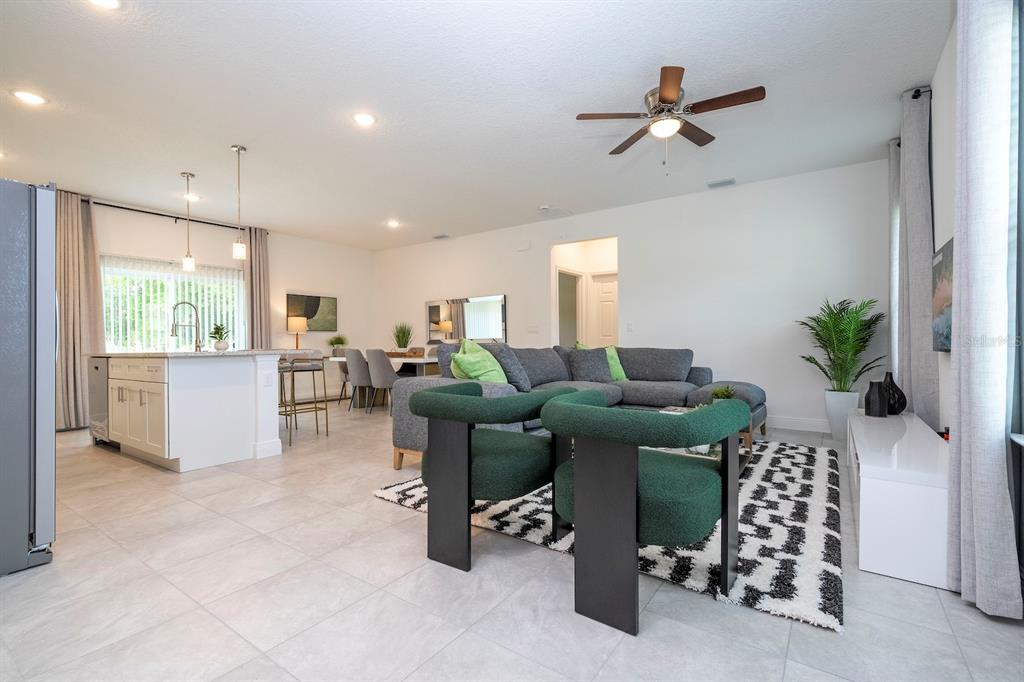 An open-concept living room and kitchen featuring gray tile floors, a sectional sofa, and chairs — 15305 SW 50TH AVENUE ROAD, OCALA, FL