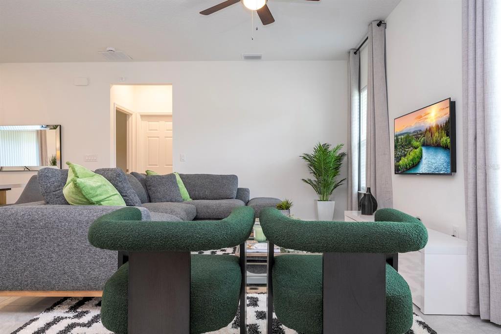 A living room features a gray sectional sofa, two green armchairs, and a wall-mounted television — 15305 SW 50TH AVENUE ROAD, OCALA, FL