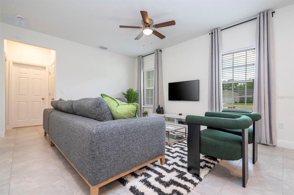 A living room features a gray sofa, two green armchairs, a patterned rug, and television — 15305 SW 50TH AVENUE ROAD, OCALA, FL