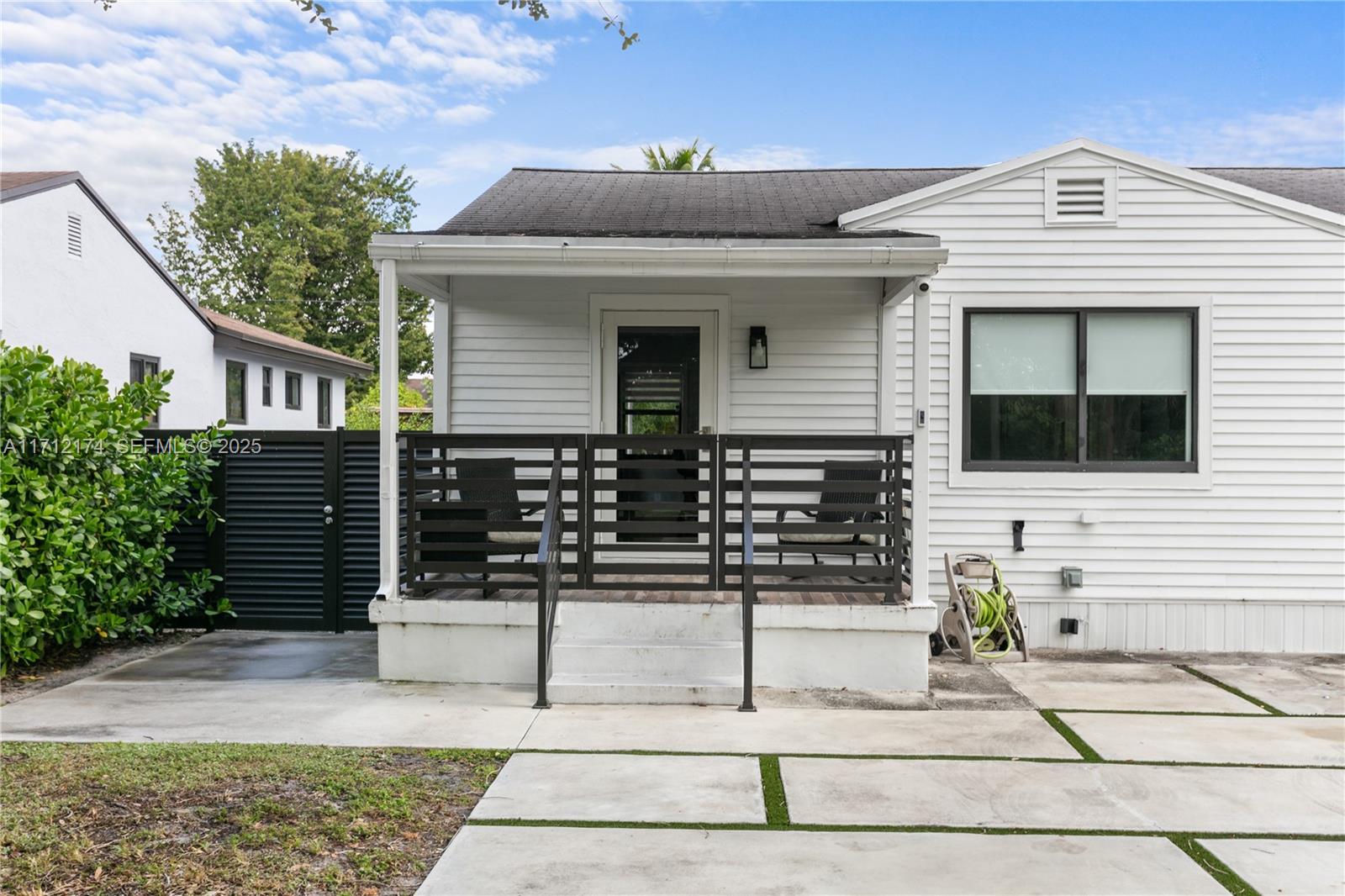 A white house features a covered front porch with dark horizontal railings and concrete steps — 341 NW 67th Ave, Miami Springs FL 33166, MIAMI SPRINGS, FL