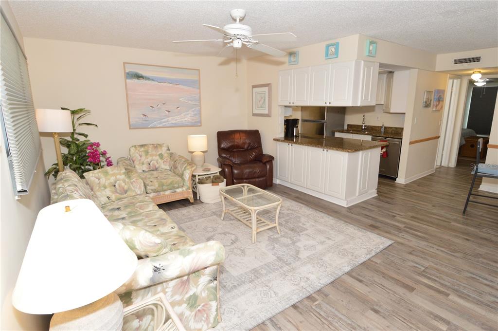 A living room with floral furniture, a brown recliner, and an open kitchen with white cabinets — 12760 INDIAN ROCKS ROAD UNIT 409, LARGO, FL