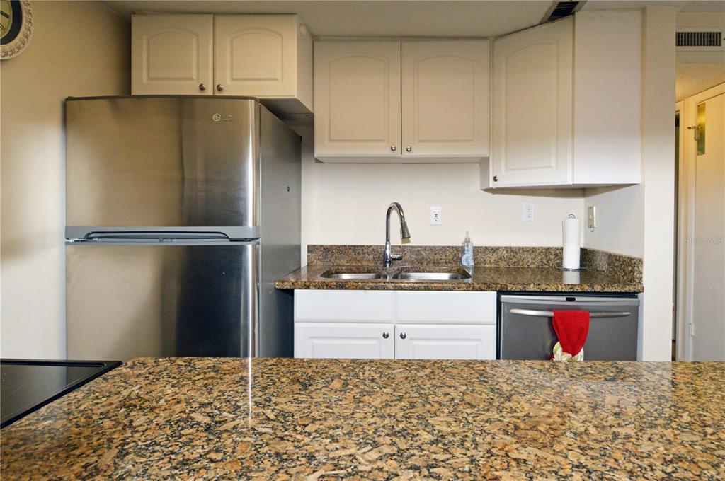 A kitchen features stainless steel appliances, white cabinets, and speckled granite countertops — 12760 INDIAN ROCKS ROAD UNIT 409, LARGO, FL