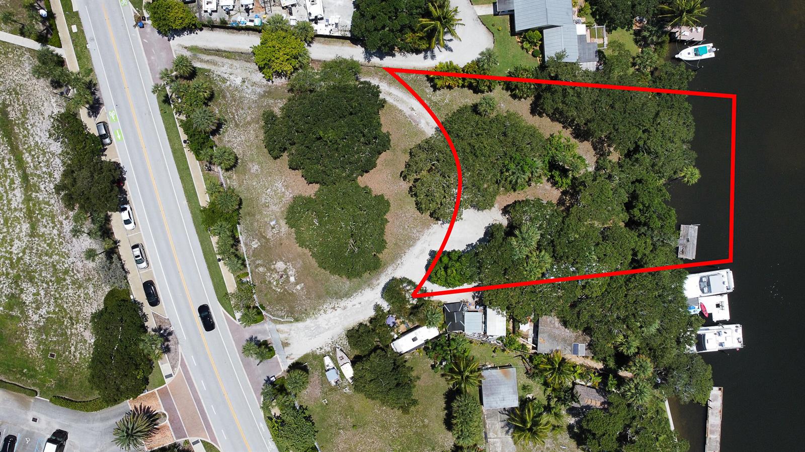 An aerial view shows a vacant, tree-covered waterfront lot outlined in red next to a road — 18011 N Highway A1a, Jupiter FL 33477, JUPITER, FL