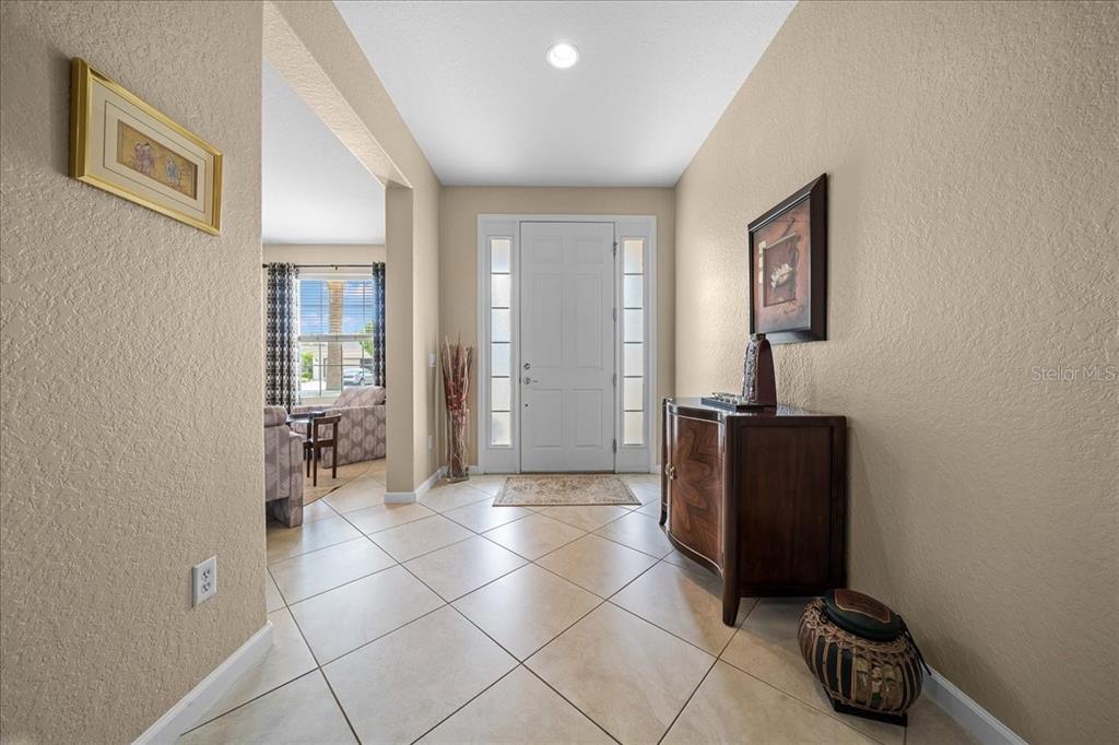 An entryway features beige walls, tile flooring, a white front door, and a wooden cabinet — 7338 SW 94TH COURT, OCALA, FL