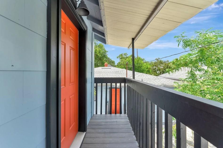 An exterior wooden balcony with a bright orange door and black railings — 828 22ND AVENUE N UNIT 1/2, ST PETERSBURG, FL