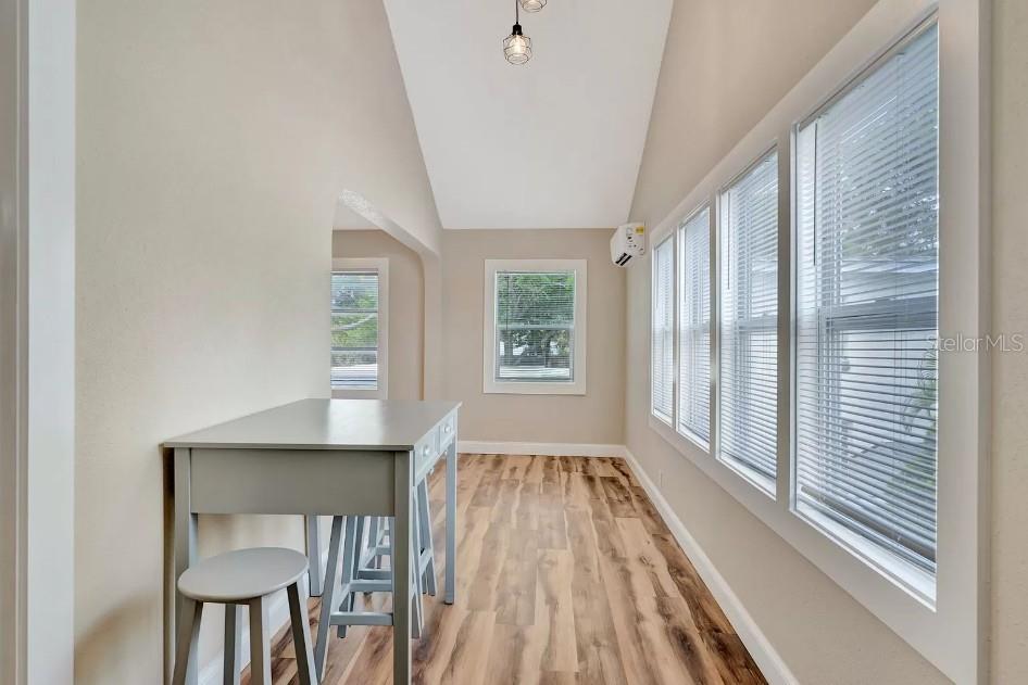A sunroom with wood-look flooring, a gray desk, and multiple windows with white blinds — 828 22ND AVENUE N UNIT 1/2, ST PETERSBURG, FL