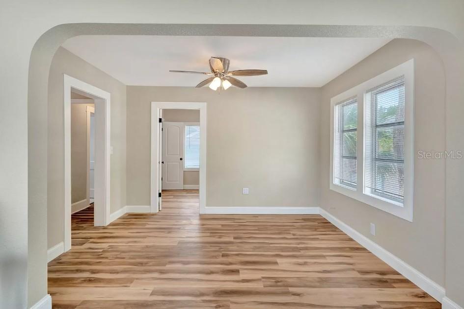 An empty room features light-colored walls, wood-look flooring, an arched entryway, and a ceiling fan — 828 22ND AVENUE N UNIT 1/2, ST PETERSBURG, FL