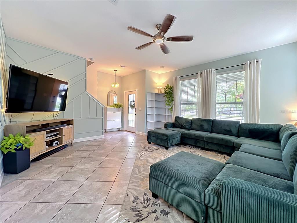 A living room features a green sectional sofa, tile flooring, and a wall with molding — 11780 STEIN STREET, ORLANDO, FL