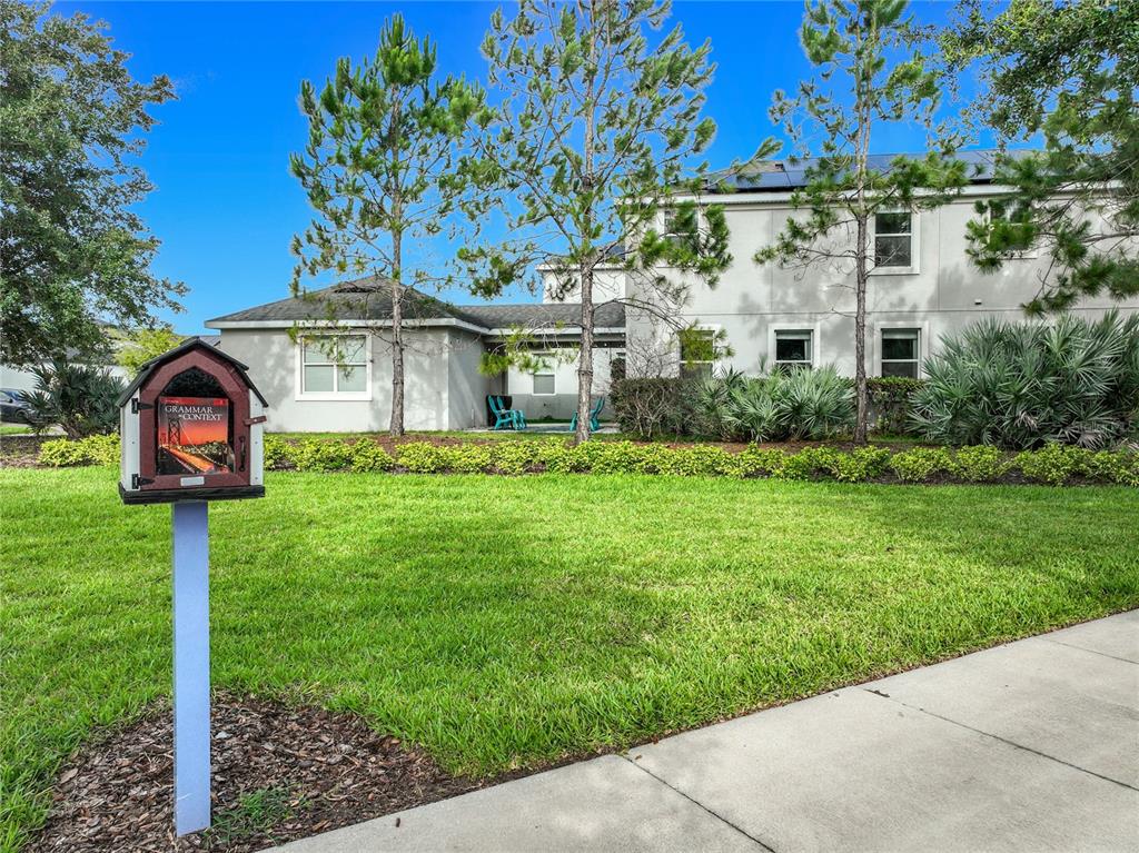 A small wooden library box stands on a lawn in front of a two-story house — 11780 STEIN STREET, ORLANDO, FL